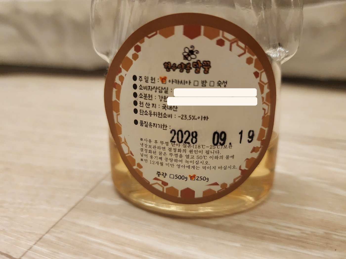 곰돌이 모양 꿀 병 뒷면 라벨 - 주밀원 아카시아, 원산지 국내산, 탄소동위원소비 -23.5‰ 이하, 품질유지기한 표시