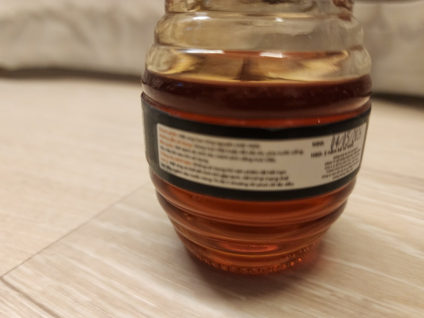 벌통 모양 꿀 병 뒷면의 외국어 라벨 - 짙은 호박색 꿀이 담겨 있음